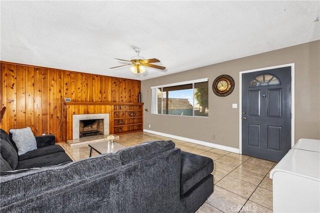 66890 Hacienda Ave, Desert Hot Springs, CA 92240 - living room with light tile patterned floors, a ceiling fan, wood walls, and a fireplace with raised hearth