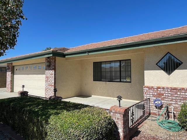1003 Amherst Ave, Hemet, CA 92544 - view of front of house featuring stucco siding, an attached garage, and brick siding