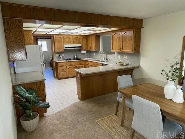 1003 Amherst Ave, Hemet, CA 92544 - kitchen featuring freestanding refrigerator, a peninsula, under cabinet range hood, and brown cabinets