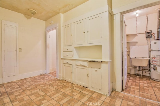 1615 W 39th Pl, Los Angeles, CA 90062 - kitchen featuring brick patterned floors, strapped water heater, and light countertops