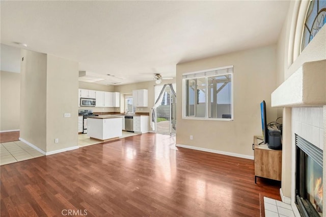 44601 Jamin Cir, Temecula, CA 92592 - unfurnished living room with a tile fireplace, a ceiling fan, and light wood-type flooring
