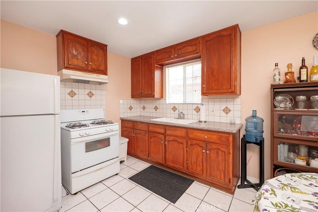 1203 E 33rd St, Los Angeles, CA 90011 - kitchen with white appliances, under cabinet range hood, light countertops, decorative backsplash, and light tile patterned floors