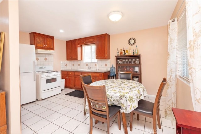 1203 E 33rd St, Los Angeles, CA 90011 - kitchen featuring white appliances, under cabinet range hood, tasteful backsplash, light countertops, and light tile patterned floors