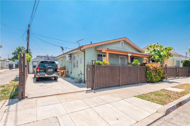 1203 E 33rd St, Los Angeles, CA 90011 - bungalow-style home with a fenced front yard, concrete driveway, an AC wall unit, and stucco siding
