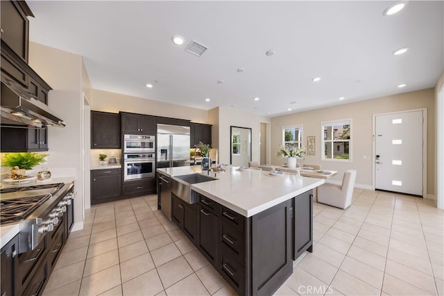 125 Character, Irvine, CA 92618 - kitchen with appliances with stainless steel finishes, light tile patterned floors, light countertops, recessed lighting, and an island with sink