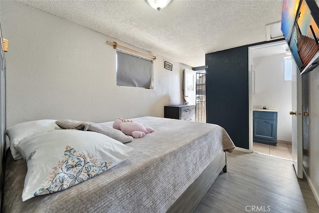 5868 Estrella Ave, Los Angeles, CA 90044 - bedroom with a textured ceiling, a textured wall, light wood finished floors, and connected bathroom