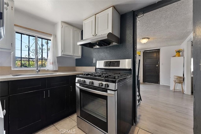 5868 Estrella Ave, Los Angeles, CA 90044 - kitchen with gas range, under cabinet range hood, white cabinets, light countertops, and dark cabinets