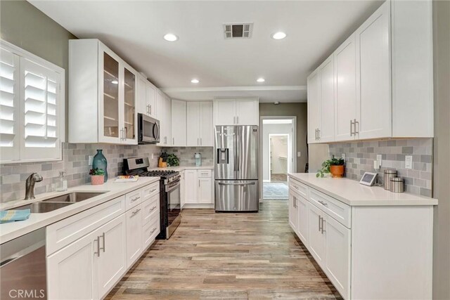 4437 Keever Ave, Long Beach, CA 90807 - kitchen featuring appliances with stainless steel finishes, light wood-type flooring, recessed lighting, white cabinetry, and tasteful backsplash