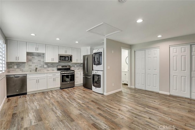 4437 Keever Ave, Long Beach, CA 90807 - kitchen featuring appliances with stainless steel finishes, stacked washing machine and dryer, light countertops, decorative backsplash, and white cabinets