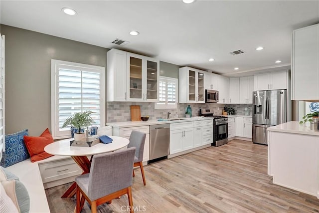 4437 Keever Ave, Long Beach, CA 90807 - kitchen featuring stainless steel appliances, tasteful backsplash, white cabinets, light countertops, and light wood-type flooring