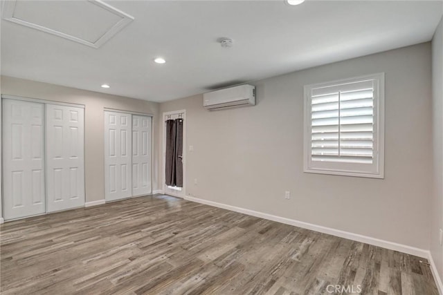 4437 Keever Ave, Long Beach, CA 90807 - unfurnished bedroom with a wall mounted air conditioner, recessed lighting, wood finished floors, two closets, and attic access