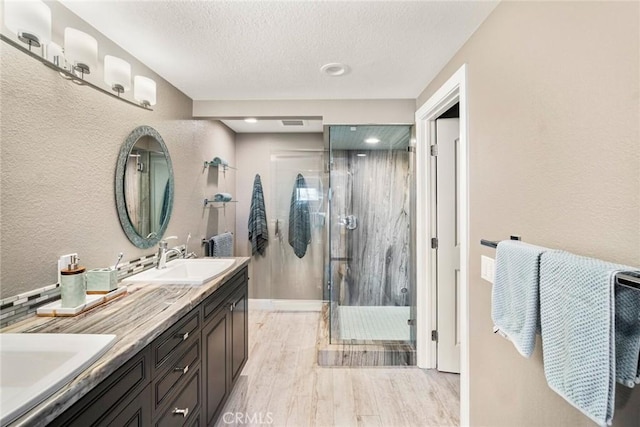 24532 Moonfire Dr, Dana Point, CA 92629 - bathroom with wood finished floors, double vanity, a shower stall, a textured ceiling, and a textured wall