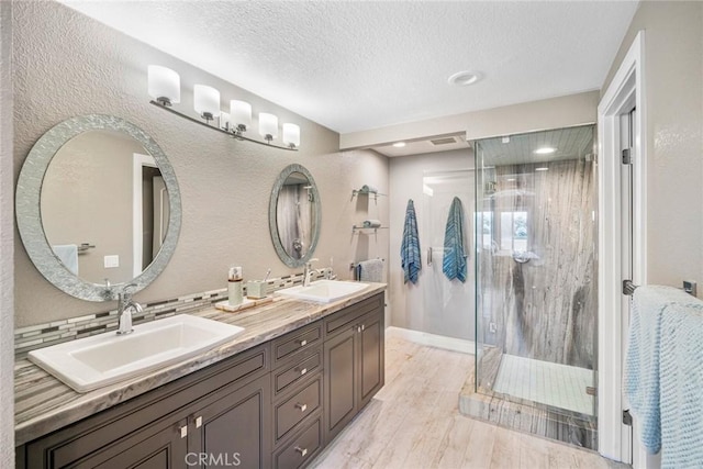 24532 Moonfire Dr, Dana Point, CA 92629 - full bath featuring double vanity, a shower stall, a textured ceiling, wood finished floors, and a textured wall