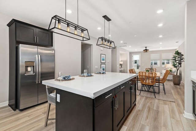3510 Brody Way, Oceanside, CA 92056 - kitchen featuring stainless steel fridge with ice dispenser, light wood-type flooring, light countertops, a kitchen island, and decorative light fixtures