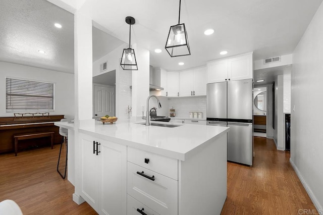 1802 Via Las Palmas Unit 36, National City, CA 91950 - kitchen featuring freestanding refrigerator, wood finished floors, tasteful backsplash, white cabinetry, and light countertops