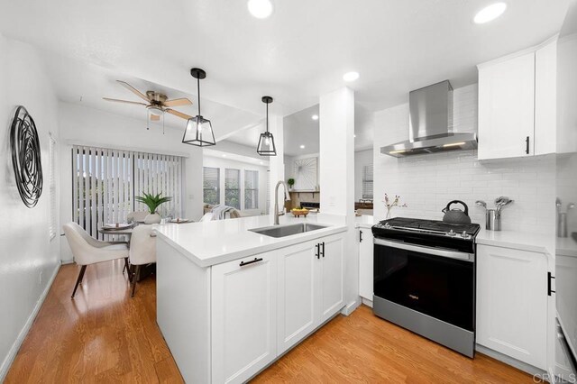1802 Via Las Palmas Unit 36, National City, CA 91950 - kitchen with wall chimney range hood, stainless steel gas range, tasteful backsplash, light wood-style floors, and recessed lighting