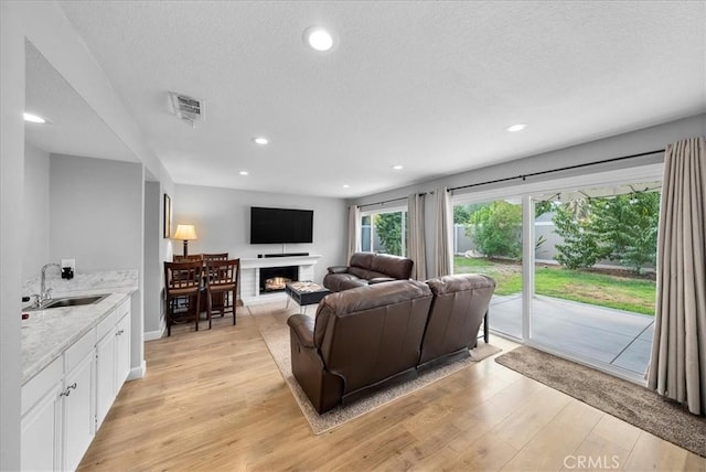 1380 Le Conte, Riverside, CA 92507 - living room with a lit fireplace, light wood-type flooring, recessed lighting, and a textured ceiling