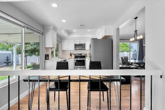 1380 Le Conte, Riverside, CA 92507 - kitchen with appliances with stainless steel finishes, white cabinets, light countertops, decorative backsplash, and light wood-style flooring