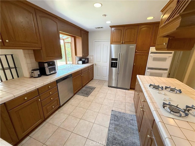 21045 Hemmingway St, Canoga Park, CA 91304 - kitchen featuring stainless steel appliances, tile counters, light tile patterned flooring, recessed lighting, and tasteful backsplash