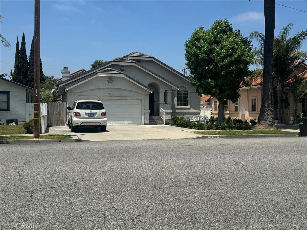 15727 Virginia Ave, Paramount, CA 90723 - view of front facade featuring an attached garage, concrete driveway, and stucco siding