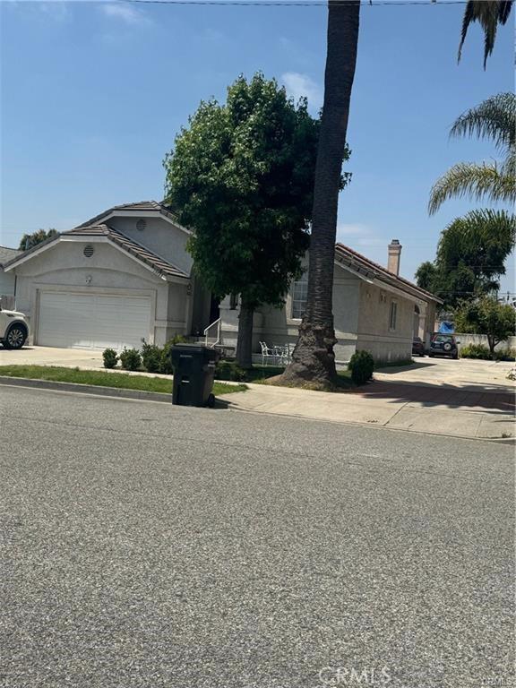 15727 Virginia Ave, Paramount, CA 90723 - view of front of home with an attached garage, concrete driveway, and stucco siding