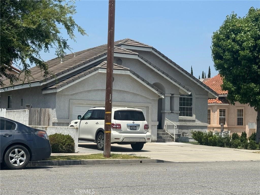 15727 Virginia Ave, Paramount, CA 90723 - view of front facade featuring a garage, driveway, a tile roof, and stucco siding