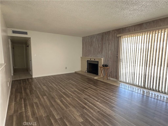 1624 Forane St, Barstow, CA 92311 - unfurnished living room featuring a textured ceiling, dark wood-style floors, a brick fireplace, and wood walls