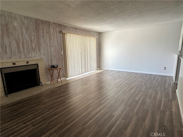 1624 Forane St, Barstow, CA 92311 - unfurnished living room with dark wood-style floors, a fireplace with raised hearth, a textured ceiling, and wooden walls