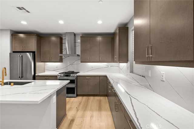 431 Daniella Way, Perris, CA 92570 - kitchen with high end appliances, wall chimney exhaust hood, light wood-style floors, light stone counters, and recessed lighting