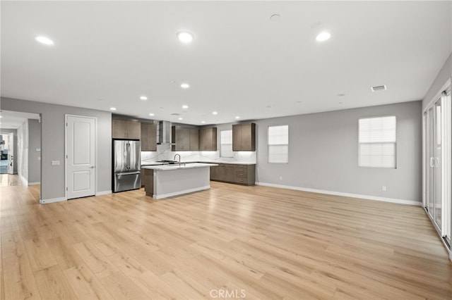 431 Daniella Way, Perris, CA 92570 - kitchen featuring freestanding refrigerator, open floor plan, a kitchen island with sink, wall chimney range hood, and light countertops