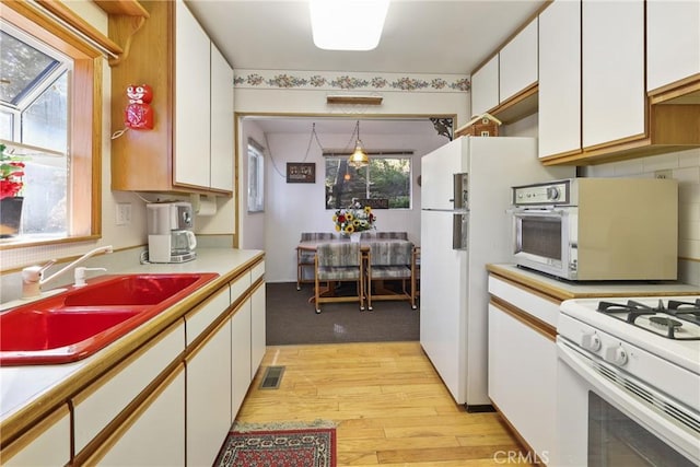 26314 Jacqueline Rd, Twin Peaks, CA 92391 - kitchen featuring white cabinets, light countertops, light wood-type flooring, white gas stove, and pendant lighting
