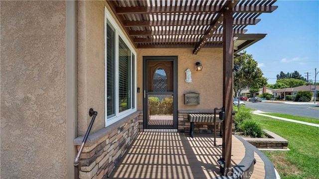 5215 E Monlaco Rd, Long Beach, CA 90808 - doorway to property featuring stucco siding, stone siding, and a pergola