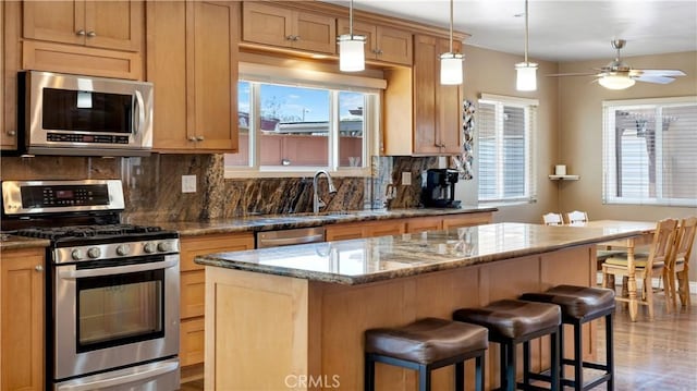 5215 E Monlaco Rd, Long Beach, CA 90808 - kitchen with stainless steel appliances, tasteful backsplash, a center island, a breakfast bar area, and dark stone countertops
