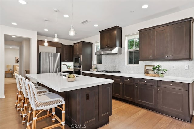 143 Hollow Tree, Irvine, CA 92618 - kitchen with stainless steel appliances, dark brown cabinetry, decorative backsplash, a kitchen bar, and recessed lighting
