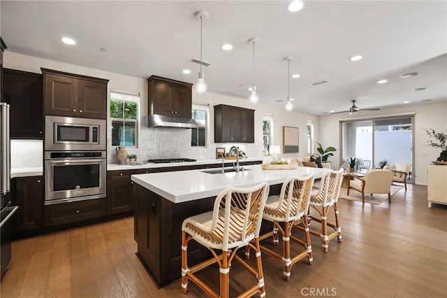 143 Hollow Tree, Irvine, CA 92618 - kitchen featuring stainless steel appliances, light countertops, open floor plan, dark brown cabinetry, and recessed lighting