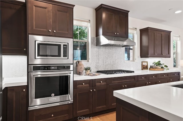 143 Hollow Tree, Irvine, CA 92618 - kitchen featuring stainless steel appliances, light countertops, decorative backsplash, dark brown cabinets, and light wood-type flooring