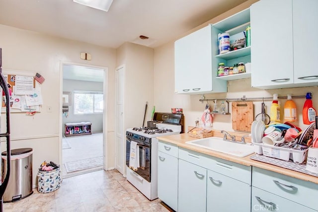 12029 Greyford St, Whittier, CA 90606 - kitchen with white gas stove, light countertops, open shelves, and white cabinetry