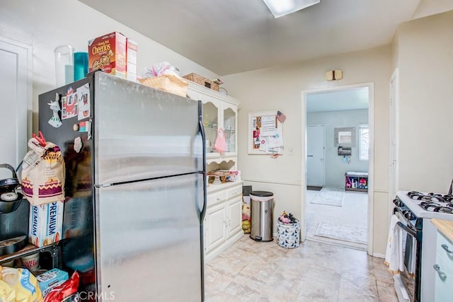 12029 Greyford St, Whittier, CA 90606 - kitchen with freestanding refrigerator, gas range, white cabinetry, and light countertops