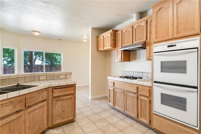 11471 Azure View Rd, Pinon Hills, CA 92372 - kitchen with white appliances, under cabinet range hood, tile counters, light tile patterned floors, and a textured ceiling