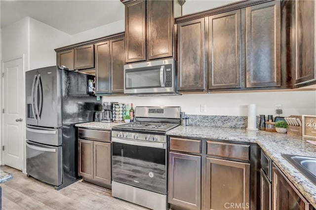2146 N Rinaldi Ct, Visalia, CA 93291 - kitchen featuring appliances with stainless steel finishes, light wood-type flooring, light stone countertops, and dark brown cabinets