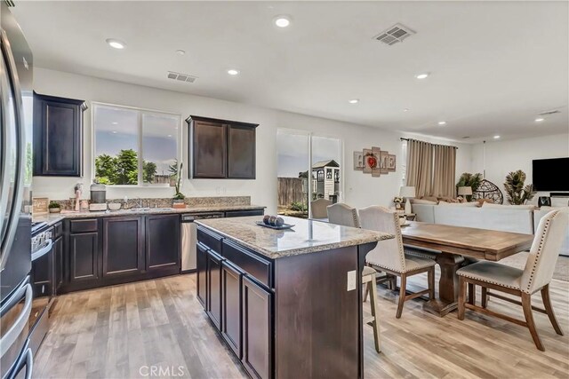 2146 N Rinaldi Ct, Visalia, CA 93291 - kitchen with appliances with stainless steel finishes, light wood finished floors, light stone countertops, a center island, and open floor plan