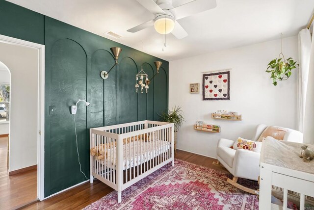 205 C St, Chula Vista, CA 91910 - bedroom with wood finished floors, arched walkways, a crib, and ceiling fan