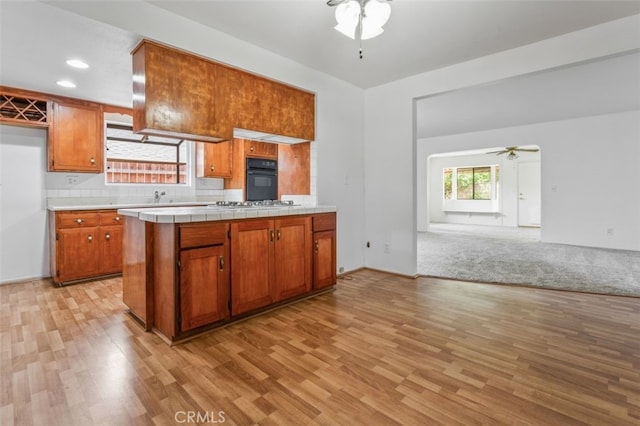 9726 Kimberly Ave, Montclair, CA 91763 - kitchen with a ceiling fan, black oven, light wood finished floors, brown cabinetry, and open floor plan