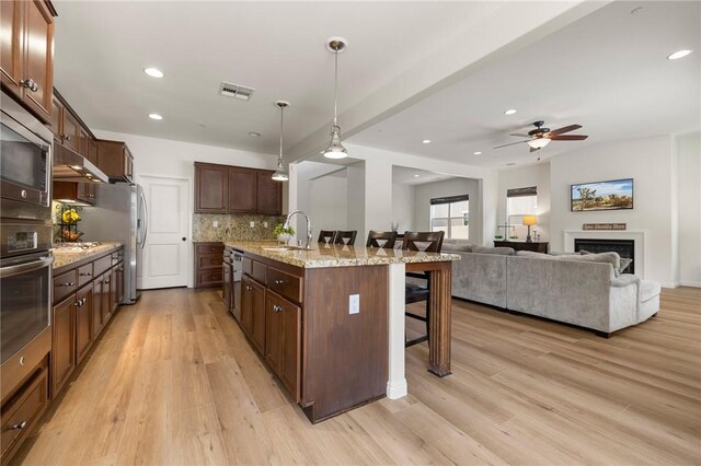 30644 Stage Coach Rd, Menifee, CA 92584 - kitchen with a kitchen bar, ceiling fan, appliances with stainless steel finishes, backsplash, and light wood-style flooring