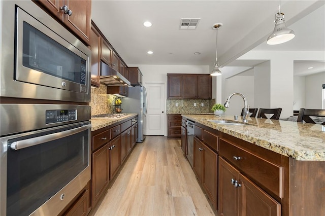 30644 Stage Coach Rd, Menifee, CA 92584 - kitchen featuring stainless steel appliances, under cabinet range hood, light wood-style flooring, backsplash, and hanging light fixtures