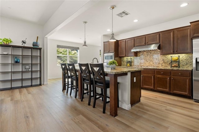 30644 Stage Coach Rd, Menifee, CA 92584 - kitchen with appliances with stainless steel finishes, under cabinet range hood, light wood-type flooring, a kitchen island with sink, and recessed lighting
