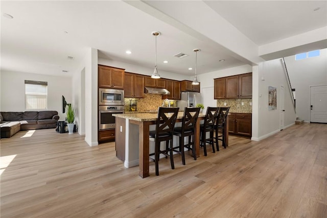 30644 Stage Coach Rd, Menifee, CA 92584 - kitchen with appliances with stainless steel finishes, under cabinet range hood, open floor plan, backsplash, and light wood-style floors