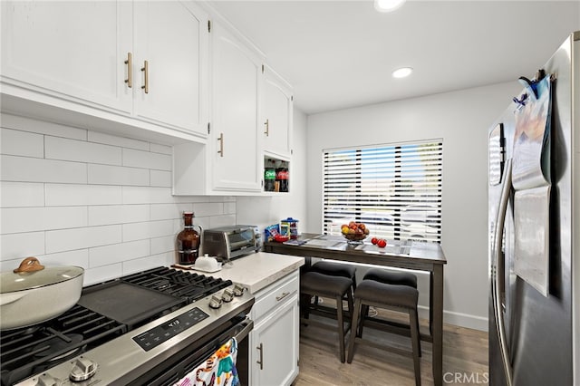 4292 Howard Ave, Los Alamitos, CA 90720 - kitchen featuring appliances with stainless steel finishes, white cabinetry, light wood-style floors, tasteful backsplash, and recessed lighting