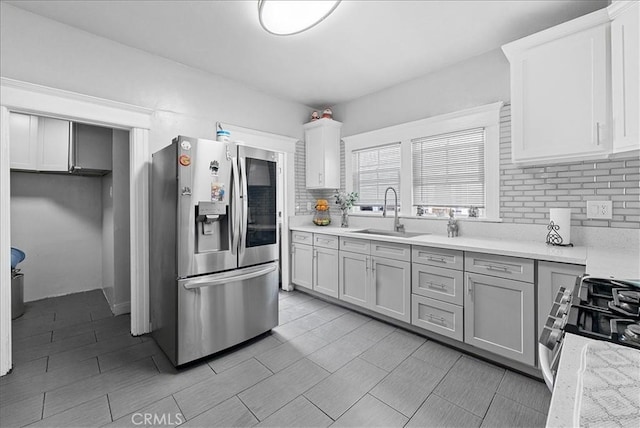 1665 Arlington Ave, Los Angeles, CA 90019 - kitchen featuring appliances with stainless steel finishes, light countertops, backsplash, and white cabinetry