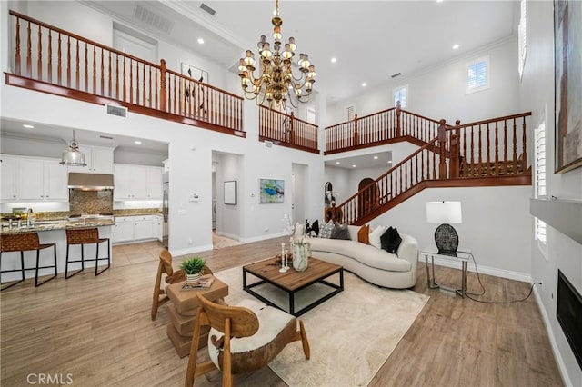 53 Interlude, Irvine, CA 92620 - living room with ornamental molding, stairway, light wood finished floors, a chandelier, and a towering ceiling